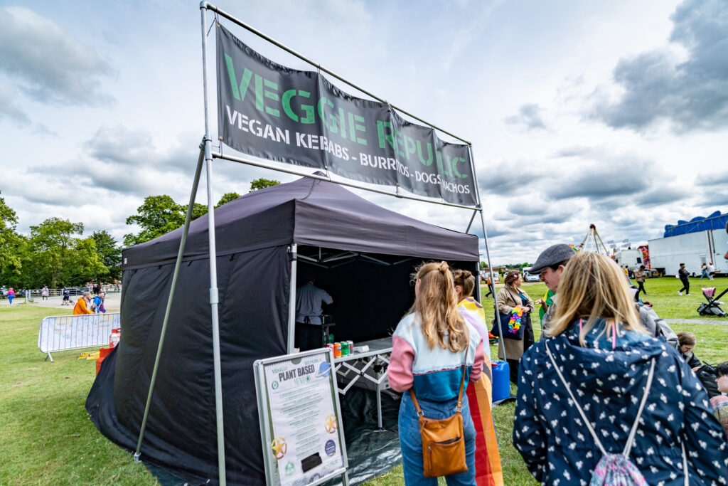 Alt text: Visitors at York Pride enjoy vegan food stall, Veggie Republic, offering plant-based options in a lively outdoor setting.