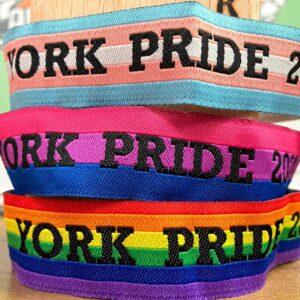Multicoloured York Pride wristbands stacked on a table, each with bold text: York Pride 2023.