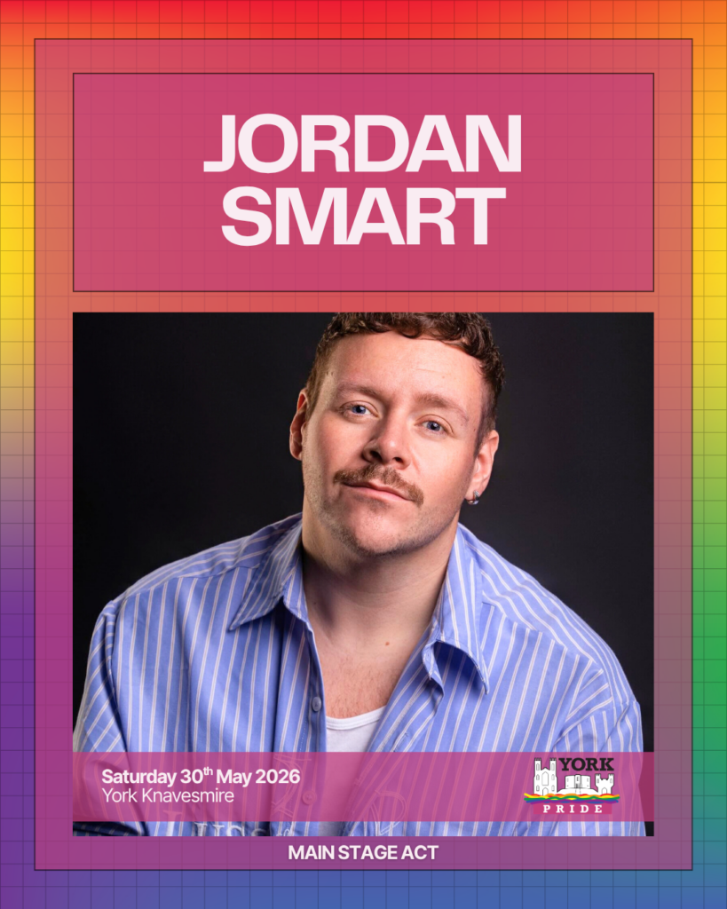 ```markdown
Alt text: Performer in a striped shirt against a rainbow grid backdrop, York Pride main stage act, 30th May 2026.
```