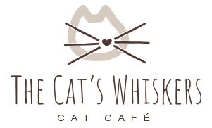 Logo for The Cat's Whiskers Cat Café featuring a stylised cat face with a heart-shaped nose and whiskers above the café name.