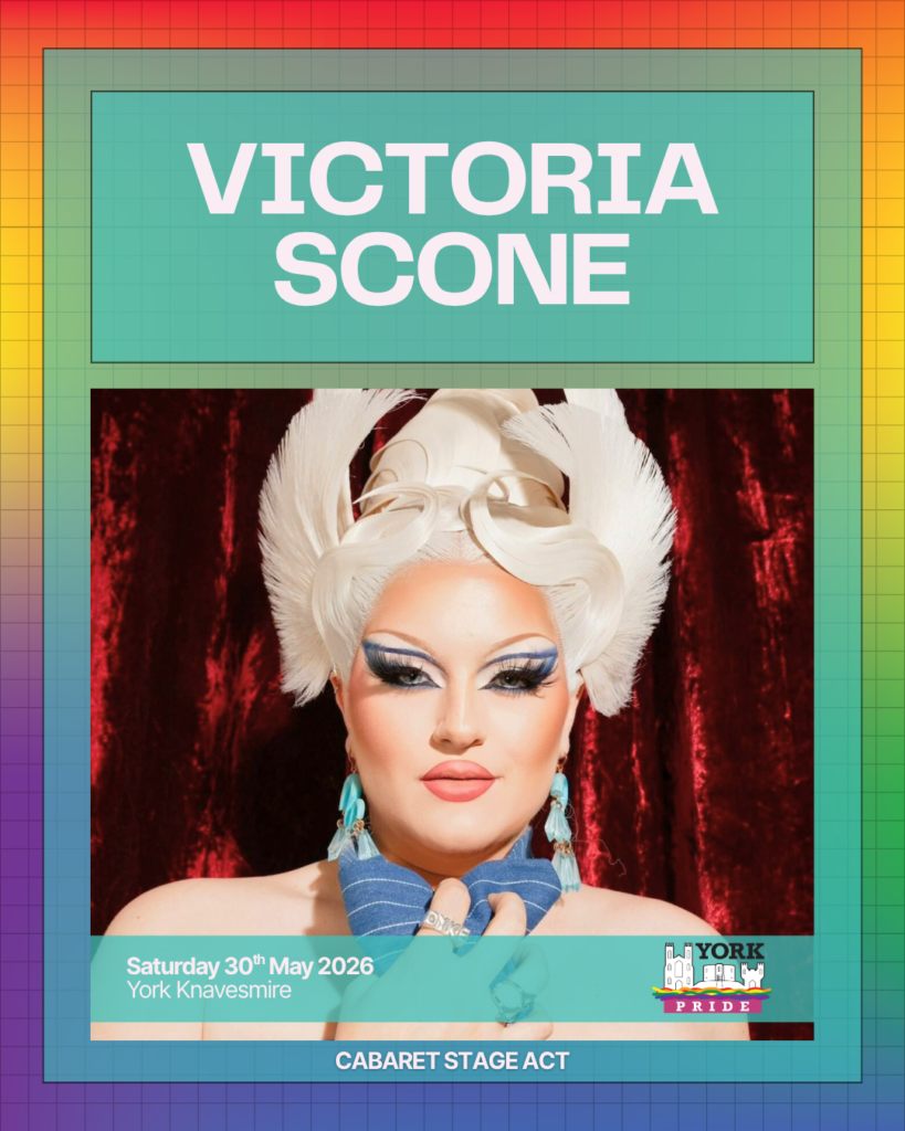 Drag performer in bright makeup and an elaborate headpiece poses against a red curtain. Text: York Pride, May 2026.
